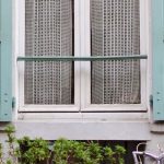 Rustic Charm - Window with green shutters on peach colored house in Paris