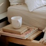 Wicker Furniture - Comfortable cozy bedroom with bed wooden shelves with book and cup while wicker basket with sticks placed on ethnic styled rug